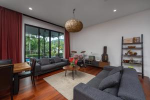 een woonkamer met twee banken en een tafel bij Baan Bua Estate Villas by TropicLook in Nai Harn Beach +223 foto's