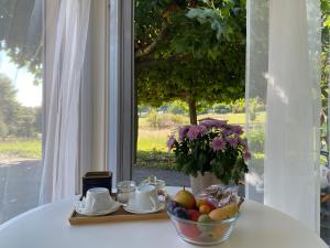 a table with a bowl of fruit on a table with a window at Le Hameau du Montchervet in Puidoux