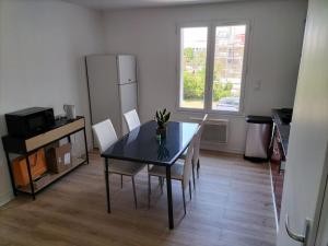 a dining room with a table and chairs and a refrigerator at Très bel appartement proche parc des expositions et aéroport Roissy CDG in Villepinte