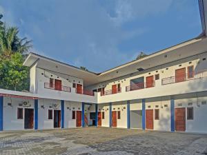 un gran edificio blanco con puertas y ventanas en SPOT ON 91995 Cvictory Inn, en Manado