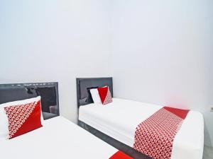 2 camas con almohadas rojas y blancas en una habitación en SPOT ON 91995 Cvictory Inn en Manado