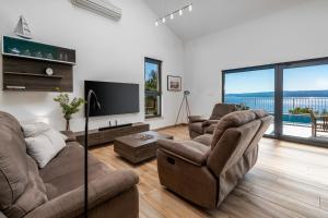a living room with two couches and a flat screen tv at Villa Oslo - luxury place with sea views & heated pool, 300m far from sandy beach in Omiš