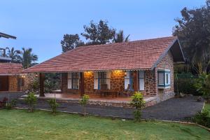 a brick house with a patio in the yard at SaffronStays Lake House Marigold, Nashik - rustic cottages with private plunge pool in Nashik