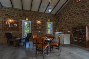 SaffronStays Lake House Marigold, Nashik - rustic cottages with private plunge pool في ناشيك: غرفة طعام مع طاولات وكراسي في جدار من الطوب