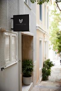 een bord aan de zijkant van een gebouw met planten bij Mandra Living-Kolonaki in Athene