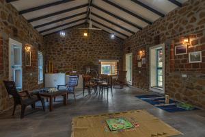 SaffronStays Lake House Marigold, Nashik - rustic cottages with private plunge pool في ناشيك: غرفة مع طاولة وكراسي في جدار من الطوب