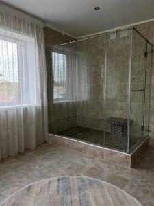 y baño con ducha y mampara de cristal. en Grand SPA Hotel en Kostanái