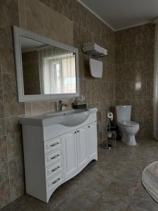 a bathroom with a sink and a mirror and a toilet at Grand SPA Hotel in Kostanay