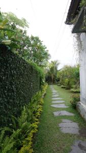 un jardín con un seto y una pasarela en Louto Dmell Guesthouse, en Sanur