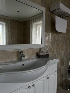 a bathroom with a sink and a large mirror at Grand SPA Hotel in Kostanay