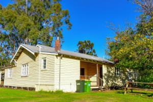 una vieja casa blanca con un cubo de basura verde en Fairbridge Village en Pinjarra