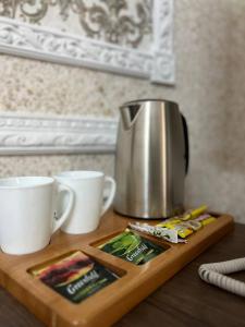 a tea kettle and two cups on a wooden cutting board at Grand SPA Hotel in Kostanay
