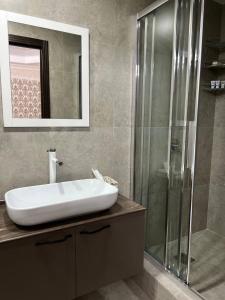 a bathroom with a sink and a glass shower at Grand SPA Hotel in Kostanay