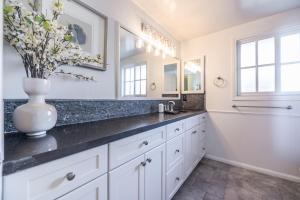 a bathroom with white cabinets and a vase with flowers on the counter at @ Marbella Lane - Serene Ranch Style Home w/Pool in Fullerton