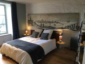 um quarto com uma cama grande e uma pintura na parede em La Maison de Mano em Plouër-sur-Rance