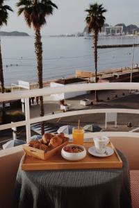 a tray of pastries and coffee on a table next to the ocean at Le Rose Thé in La Ciotat