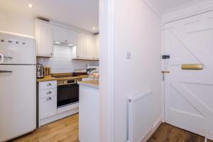 a kitchen with white cabinets and a white refrigerator at Country Charm Cottage Sleeps 4 & Free Parking in Chester