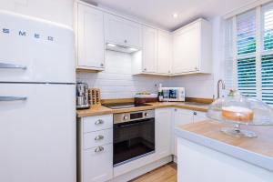 een keuken met witte kasten en een witte koelkast bij Country Charm Cottage Sleeps 4 & Free Parking in Chester