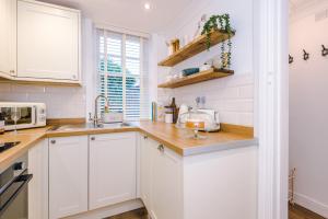 a white kitchen with white cabinets and a sink at Country Charm Cottage Sleeps 4 & Free Parking in Chester