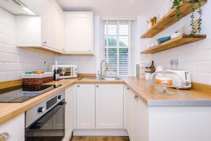 a white kitchen with white cabinets and a sink at Country Charm Cottage Sleeps 4 & Free Parking in Chester