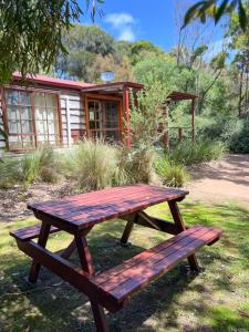 una mesa de picnic de madera frente a una cabaña en Port Bayou Cottage, en Port Campbell