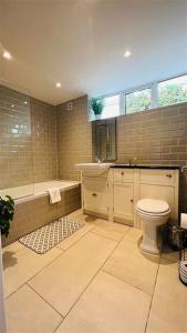 a bathroom with a toilet and a bath tub at The Retreat Birchwood by Kasar Stays in Kent