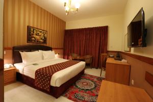 um quarto de hotel com uma cama e uma televisão de ecrã plano em NEW CALIFORNIA HOTEL no Dubai