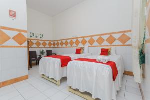 two beds with red and white sheets in a room at RedDoorz Syariah at Mojosari in Mojokerto