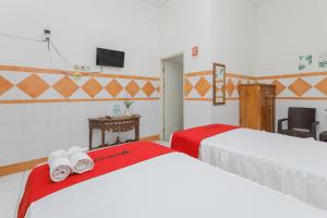 a room with two beds with red and white sheets at RedDoorz Syariah at Mojosari in Mojokerto