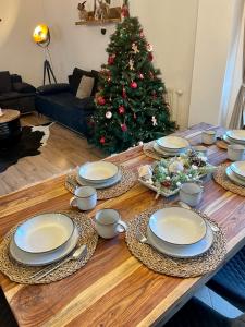 a wooden table with plates and a christmas tree at Apartmán MATEO Donovaly in Donovaly