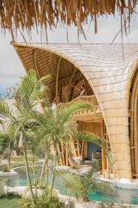 un complejo con techo de paja y palmeras en Villa Tokay - Luxury Private Villas en Gili Air