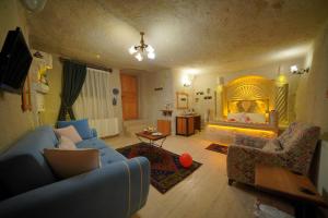 a living room with a blue couch and a bed at Fosil Cave Hotel in Ortahisar