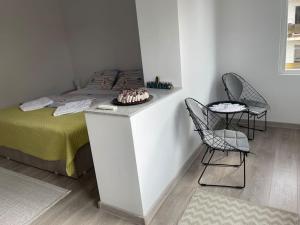 a bedroom with a bed with two chairs and a cake on a counter at Lady M Apartment in Sighişoara