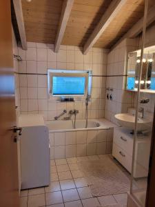 a bathroom with a tub and a sink and a window at Ferienwohnung Hegau in Hilzingen