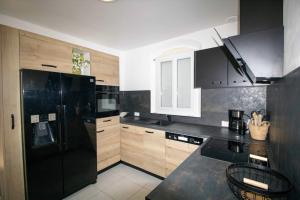 kuchnia z czarną lodówką i drewnianymi szafkami w obiekcie Quiet villa with garden and terrace in Fréjus w Fréjus