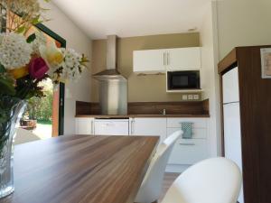 uma cozinha com uma mesa de madeira e um vaso de flores em Village de Gîtes Nature et Jardin em Bouère