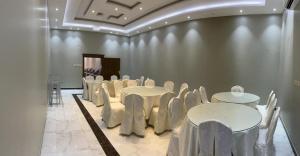 uma sala com mesas brancas e cadeiras em شاليه ريست 1 em Hail