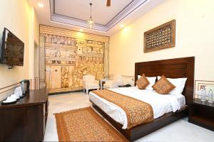 ein Hotelzimmer mit einem Bett und einem Schreibtisch und einem Zimmer in der Unterkunft Aaram Baagh Maheshwar in Maheshwar