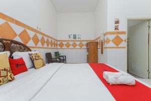 1 dormitorio con 1 cama blanca grande con almohadas coloridas en RedDoorz Syariah at Mojosari, en Mojokerto