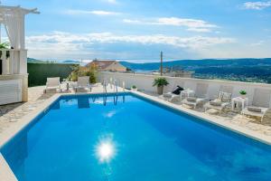 a large blue swimming pool with lounge chairs at Lovely Lucia's house in Dubrovnik