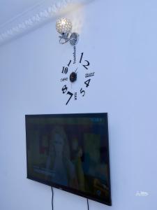 NAIVELI-PALM Appartement meublé sobre et chic في دوالا: ساعة فوق التلفزيون بشاشة