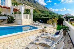 eine Terrasse mit einem Pool und Stühlen sowie ein Haus in der Unterkunft Lovely Lucia's house in Dubrovnik