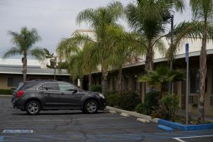 a black car parked in a parking lot with palm trees at Sands Motel by Ontario Airport & Toyota Arena in Ontario