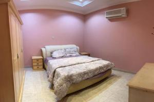 ein Schlafzimmer mit einem Bett in einem Zimmer mit rosa Wänden in der Unterkunft شالهيات ريست 2 in Ha'il