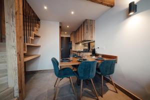 uma cozinha com uma mesa de madeira e cadeiras azuis em Studio Interlude by ExplorHome em Tignes