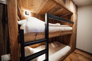 Ce lit se trouve dans un dortoir doté de 2 lits superposés et de murs en bois. dans l'établissement Studio Interlude by ExplorHome, à Tignes