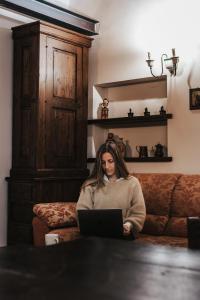 a woman sitting on a couch using a laptop at Monte Pratello - Dimora Rosy in Roccaraso