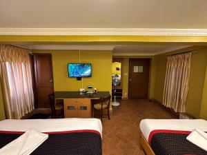 a hotel room with two beds and a desk and a television at Hotel Empire & Rooftop Restaurant in Bhaktapur