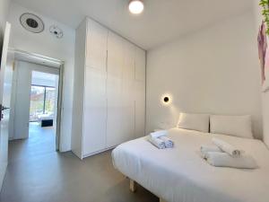 a white bedroom with a large bed with towels on it at 12 Shimon HaTzadik - By Beach Apartments TLV in Tel Aviv