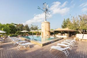 a pool with white lounge chairs and a windmill at Hotel Rural Xereca in Puig D’en Valls